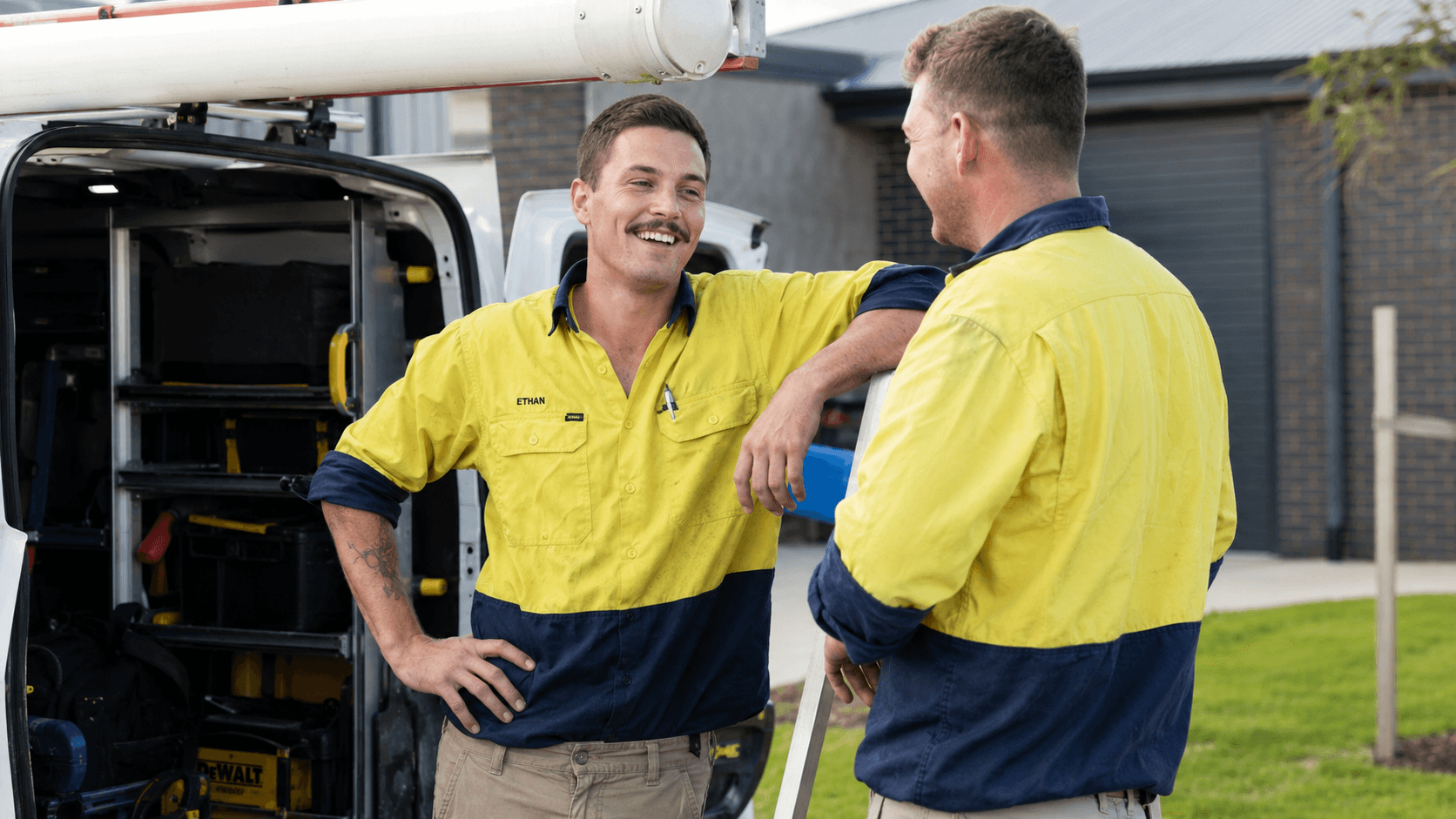 Electricians talking beside a work van in metro Australia